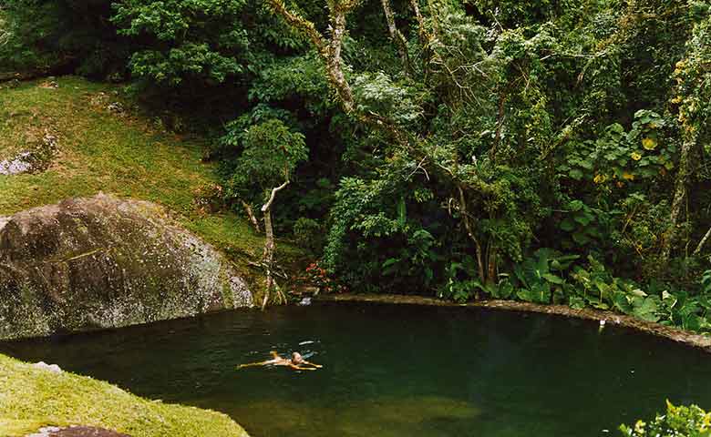 Aninhada com simplicidade e leveza sobre a sinuosidade da montanha tropical, o designer-surfista Carlos Motta ergueu seu retiro campestre numa espetacular área de preservação da Mata Atlântica